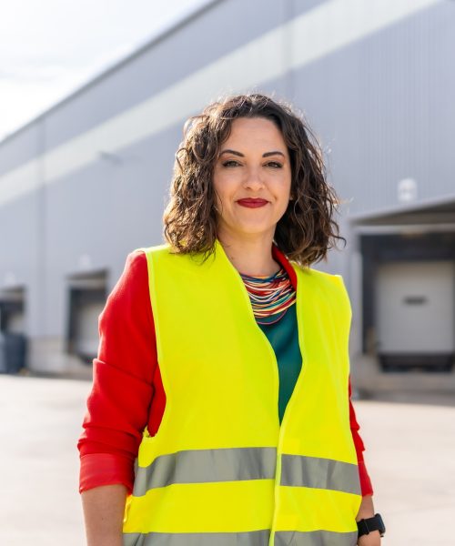 Woman manager standing with safety clothes outside a warehouse